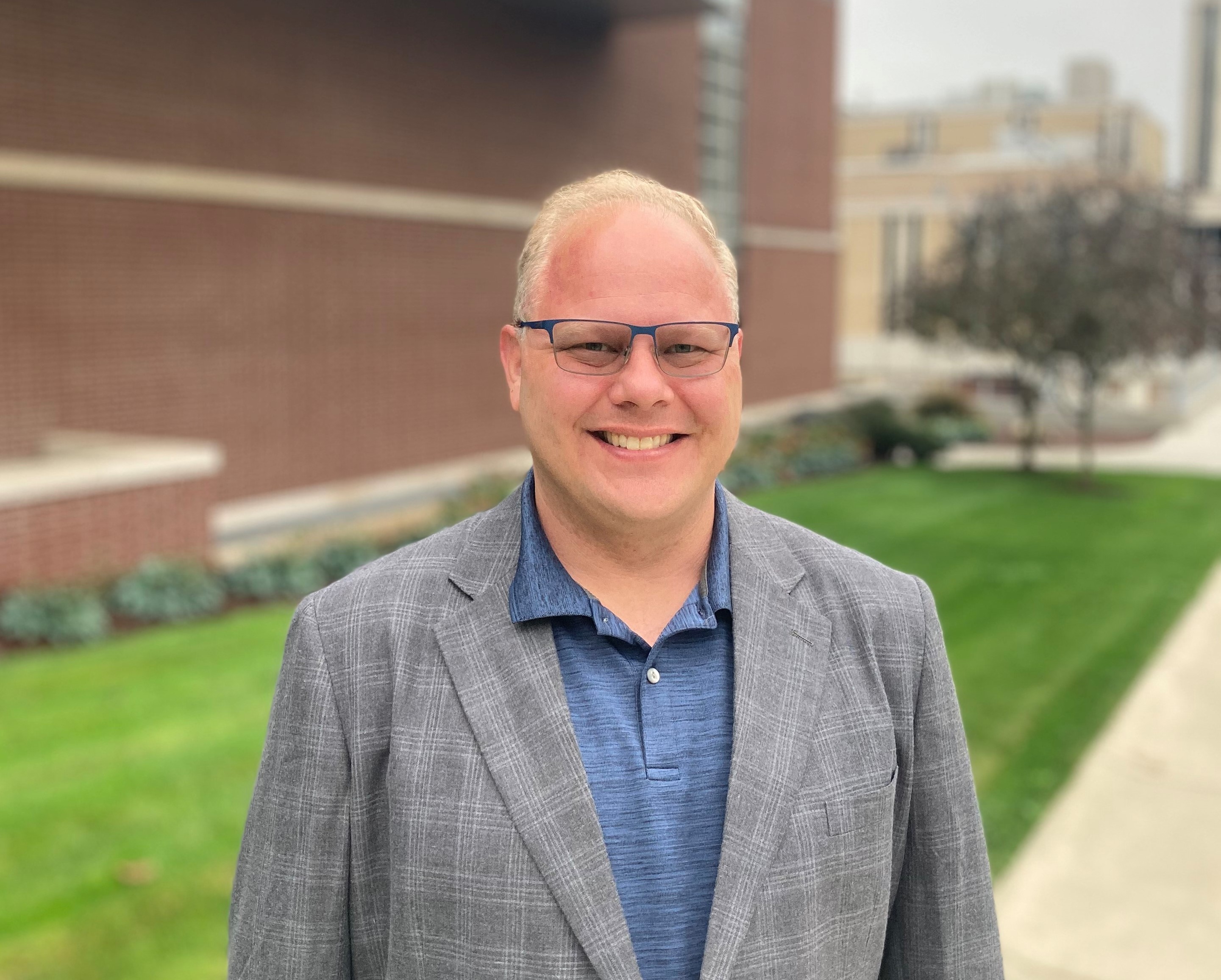 Caucasian man wearing polo shirt and blazer smiling into camera